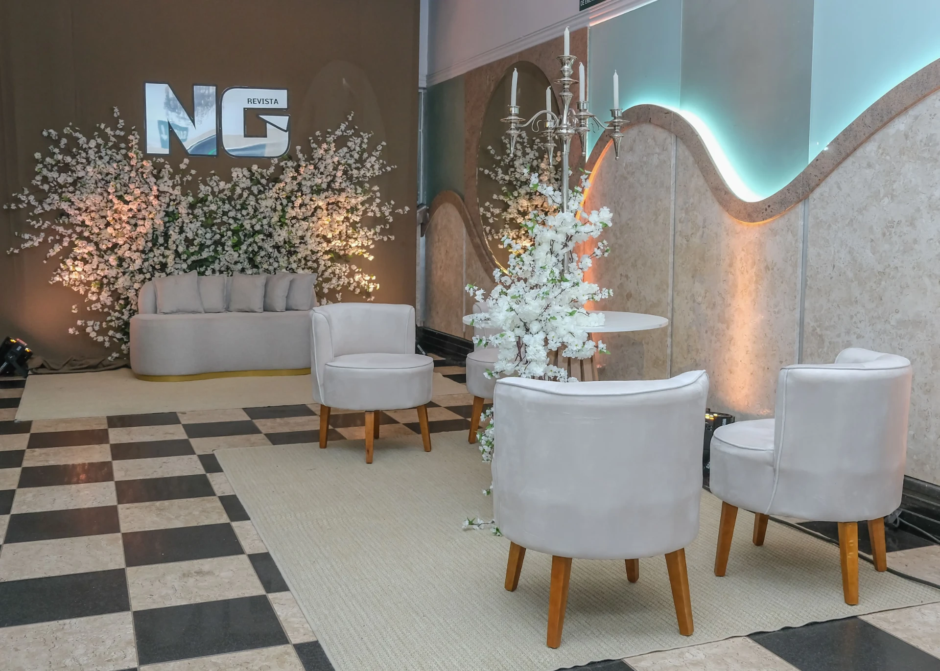 Lounge de recepção corporativa com sofá, poltronas e parede florida