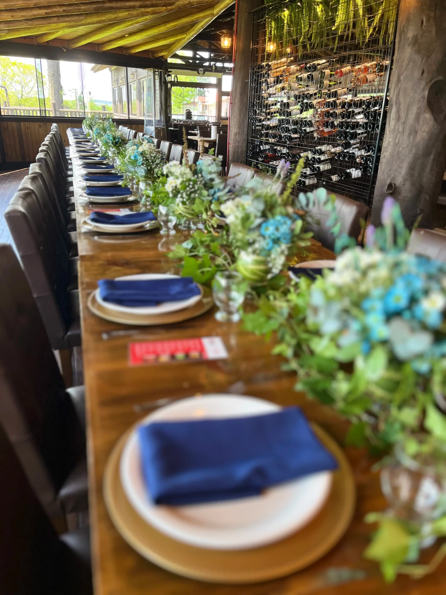 Mesa longa de jantar corporativo com caminho de flores campestres