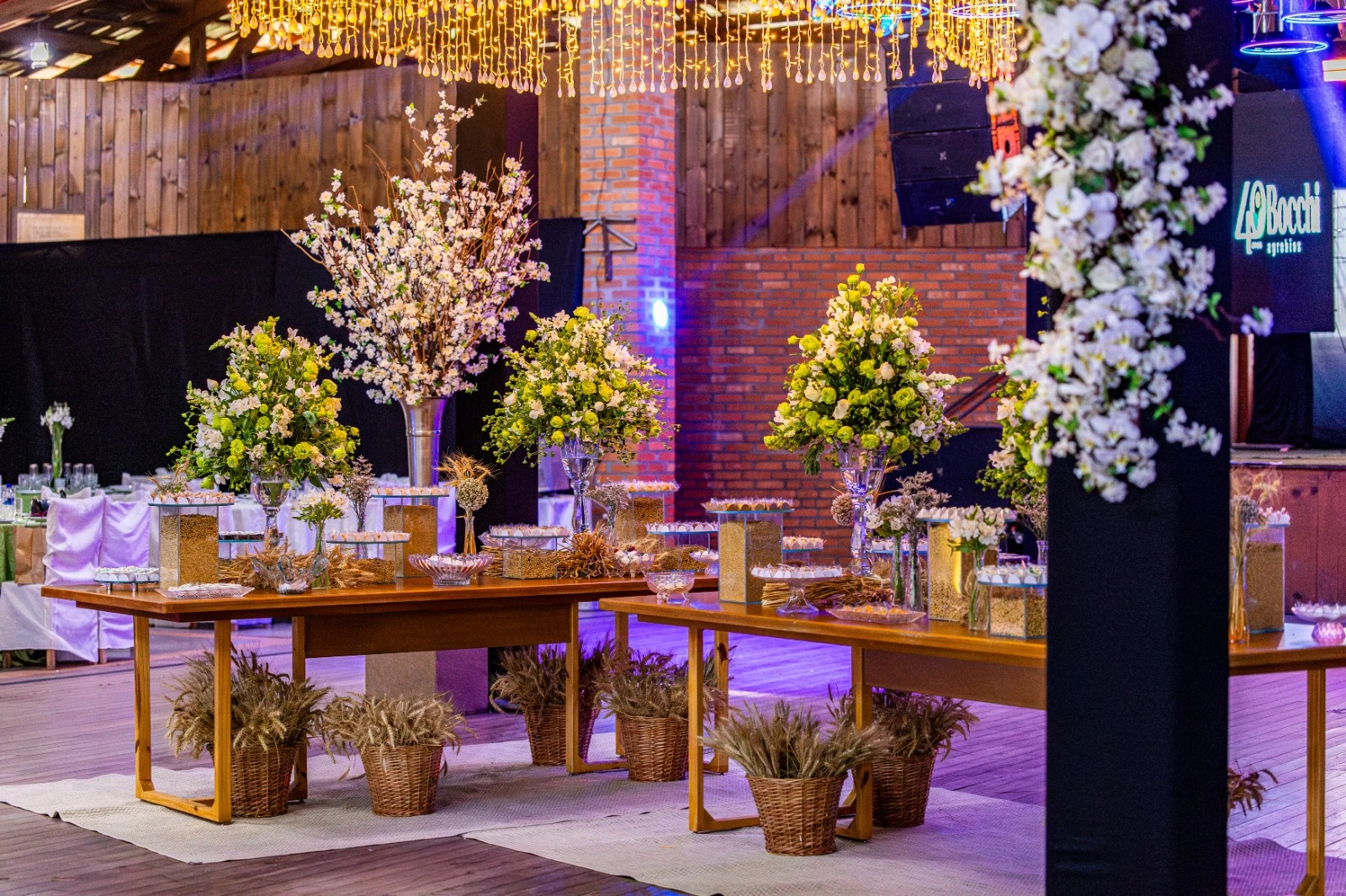Mesas de doces do casamento com arranjos florais e lustre de luzes