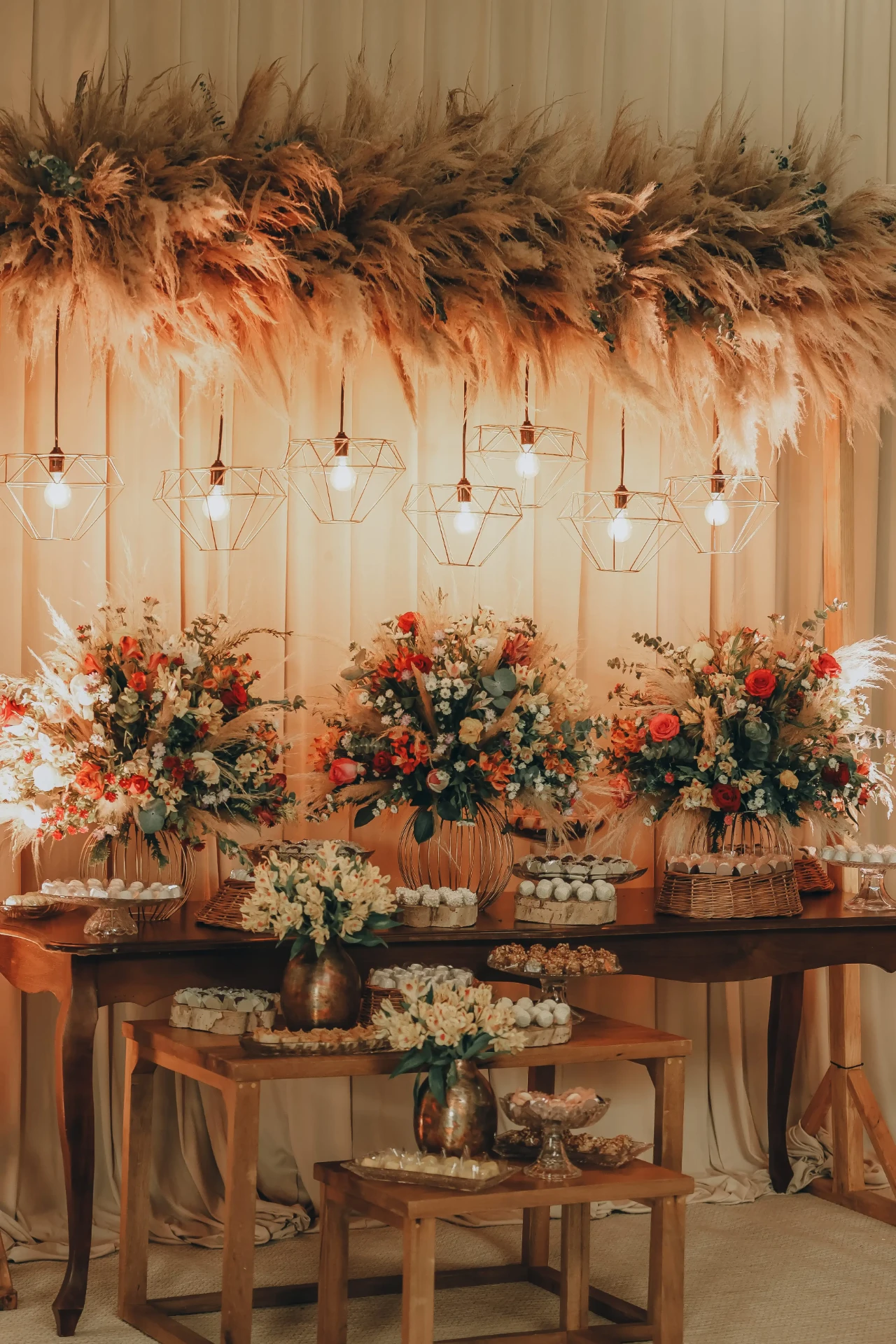 Mesa de doces rústica com pampas e arranjos coloridos